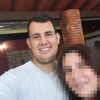 Víctor Basualdo sonríe hacia la cámara en un entorno de reunión con paredes de ladrillo.