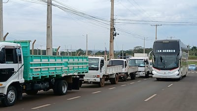 Camiones y autobús en el puente, con cielo nublado y postes de luz de fondo.