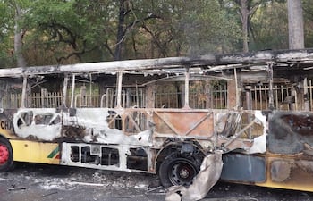 Un bombero termina de sofocar el fuego en el colectivo de La chaqueña reducido a una carcaza, frente al Jardín Botánico de Asunción.