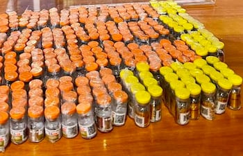 Varios frascos de medicamentos dispuestos sobre madera, con tapas en tonos naranja y amarillo.