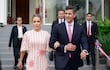 Leticia Ocampos en vestido claro y Santiago Peña Santi en traje oscuro, caminando juntos entre asistentes en un evento formal al aire libre.