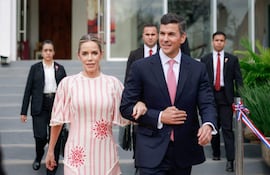 Leticia Ocampos en vestido claro y Santiago Peña Santi en traje oscuro, caminando juntos entre asistentes en un evento formal al aire libre.