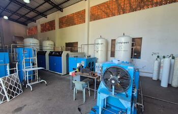 Interior del taller con equipos industriales grandes y botellas de gas. Sin presencia de personas.