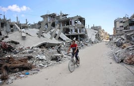 Un joven palestino cruza en bicicleta una zona afectada por bombardeos israelíes en Beit Lahia, en el norte de la Franja de Gaza, el lunes.