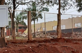 Cartel de la Escuela Básica N° 975 San Miguel, con lema 'Educación es compromiso' y ruinas visibles de un edificio escolar.