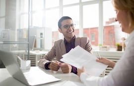 Un joven empresario de éxito y su colega discuten documentos o ideas de trabajo.