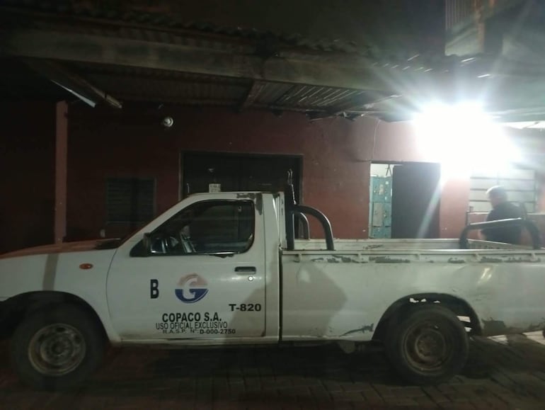 Pickup blanca de COPACO S.A. en ambiente urbano, con un hombre de pie al fondo junto al vehículo.