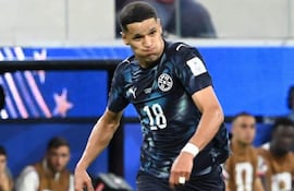 Alex Arce con camiseta oscura y el número 18, en movimiento en un estadio. Jugadores en la banca observan el partido.