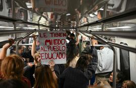 Una mujer sostiene una pancarta con el lema "Le tienen miedo a la gente educada" en un vagón del metro, luego de que estudiantes universitarios y trabajadores se reunieran en la Plaza de Mayo para participar en una protesta contra las políticas del gobierno de Javier Milei en Buenos Aires el pasado 12 de mayo
