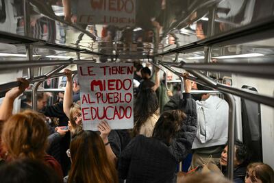 Una mujer sostiene una pancarta con el lema "Le tienen miedo a la gente educada" en un vagón del metro, luego de que estudiantes universitarios y trabajadores se reunieran en la Plaza de Mayo para participar en una protesta contra las políticas del gobierno de Javier Milei en Buenos Aires el pasado 12 de mayo