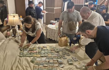 El fiscal Federico Leguizamón (camisa blanca) y sus funcionarios cuentan el dinero encontrado en la casa de Dalia López en Asunción.