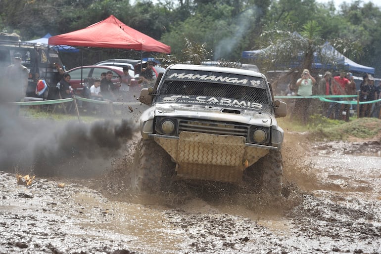 Vehículo todoterreno levantando barro en competencia, rodeado de espectadores en un día soleado en el Club Cateura.
