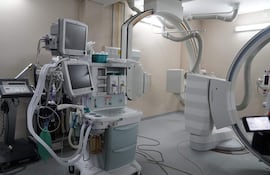 Sala de procedimientos médicos con equipos como monitor de signos vitales y máquina de anestesia, sin personas visibles.