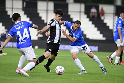 El delantero de Libertad, Rodrigo Villalba maneja el esférico en medio de las marcas de Édgar Páez (14) y Valentín Larralde, del Sportivo Ameliano.