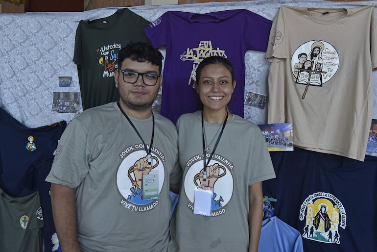 Iván Ricardi y Samira Abdalá, coordinadores de la Pascua Joven en Santísima Trinidad, junto con las remeras de las actividades en las que han participado como grupo juvenil.