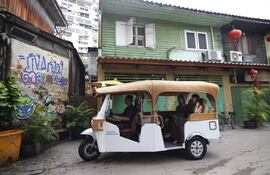 Personas viajan en un auto rickshaw eléctrico, conocido localmente como tuk-tuk, durante un recorrido por el casco antiguo de Talat Noi en Bangkok.