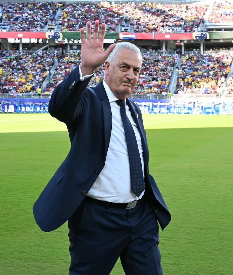 Gustavo Alfaro, con traje oscuro y corbata, saluda a la multitud en el estadio lleno de aficionados.