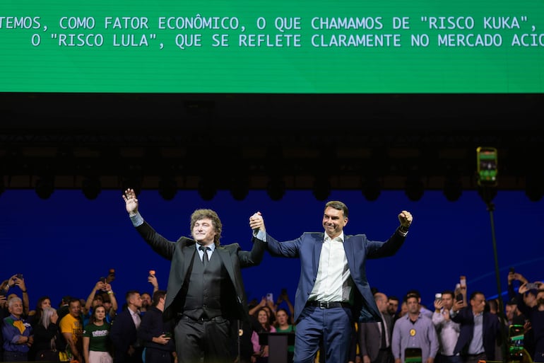 El senador de Brasil Flávio Bolsonaro (d) y el presidente de Argentina, Javier Milei (i), reaccionan en la convención nacional del Partido Liberal de Brasil (PL).