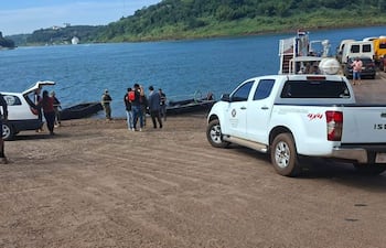 Grupo de seis personas en muelle, un hombre con casco supervisa actividades cerca de un vehículo Isuzu blanco.
