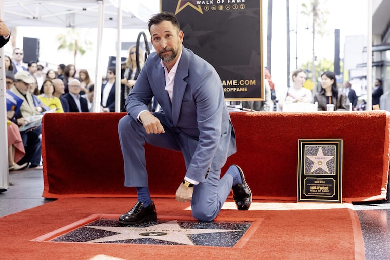 El actor estadounidense Noah Wyle se arrodilla sobre su estrella recién inaugurada en el Paseo de la Fama de Hollywood. (EFE/EPA/TED SOQUI)