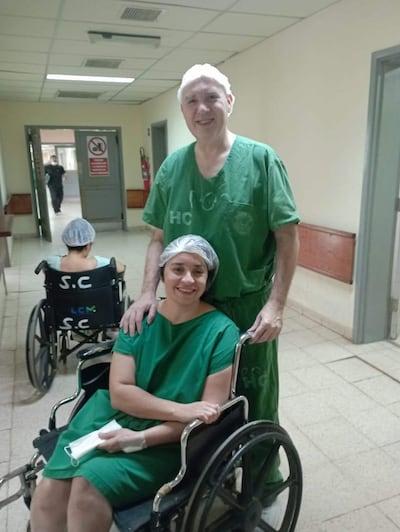Patricia Sánchez en silla de ruedas sonríe mientras conversa con un hombre con ropa de hospital.