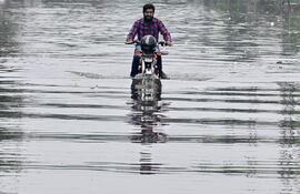 Un hombre cruza este miércoles en motocicleta una zona inundada de Lahore, Pakistán.