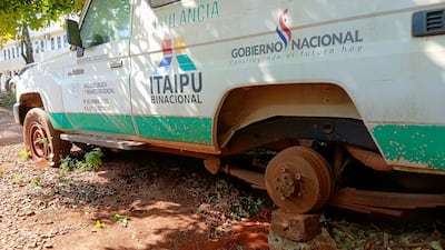 Ambulancia del Ministerio de Salud, con logos de Itaipú y Gobierno, en terreno descuidado, con llantas en mal estado.