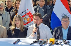 Acuña en camisa blanca y corbata gris habla al público, rodeado de asistentes en un evento oficial al aire libre.