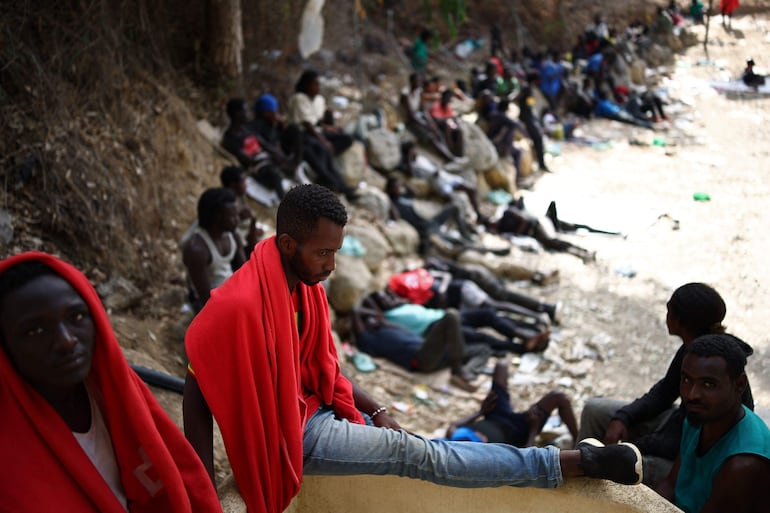Un grupo de migrantes permanece sentado en el exterior del Centro de Estancia Temporal de Inmigrantes (CETI) en el enclave español de Ceuta.