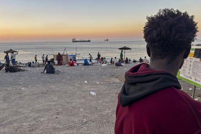 Grupos de personas migrantes en la playa El trampolín de Ceuta al atardecer.