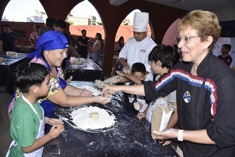 La maestra Myriam Vera (d) transmite sus enseñanzas culinarias a los pequeños de la Loma San Jerónimo.
