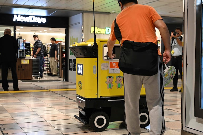 Un pasajero deposita residuos en un contenedor de basura robótico móvil que está siendo probado en el complejo de transporte de la estación de Shinjuku, en Tokio, el 18 de septiembre de 2026.