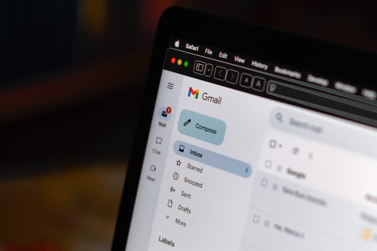 Usuario anónimo frente a ordenador portátil navegando en Gmail, con la pantalla visible llena de detalles.