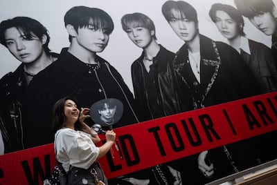 Una fan de BTS posa frente a un cartel de la banda en Tokio, Japón.