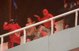 Un aficionado chileno ensangrentado es agredido por un fanático argentino, en las gradas del estadio de Independiente de Avellaneda. (AFP)