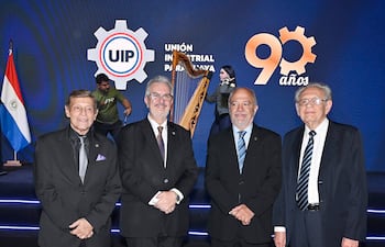 Eduardo Felippo y Enrique Duarte Luraghi conversan en un evento formal, vestidos con trajes oscuros y corbatas, con el logo de UIP al fondo.