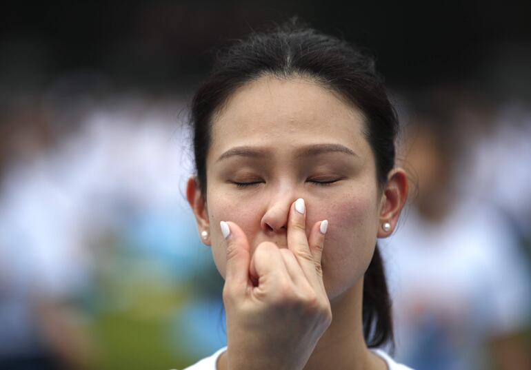 Una practicante de yoga respira con un mudra durante una sesión de yoga por el Día Internacional del Yoga.