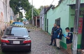 Agentes del Departamento de Criminalística inspeccionan el vehículo del oficial de la Policía Nacional.