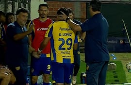 El joven zaguero central, Oliver López recibe las palabras de aliento del entrenador Hernán Rodrigo López y de los demás integrantes de la banca de suplentes del Sportivo Luqueño.