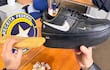 Manos sosteniendo un par de zapatillas Nike negras y un objeto envuelto en plástico en un entorno de oficina con emblema de Receita Federal.