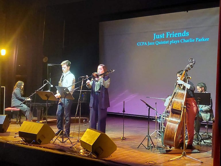 Quinteto de jazz con pianista, saxofonista, trombonista, contrabajista y baterista, iluminados en un ambiente íntimo.