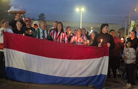 Grupo de personas con velas y una bandera paraguaya, en un ambiente de protesta al anochecer.