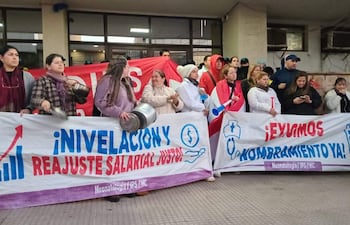 Grupo de mujeres manifestándose con pancartas que demandan reajuste salarial justo, en exterior durante una protesta.