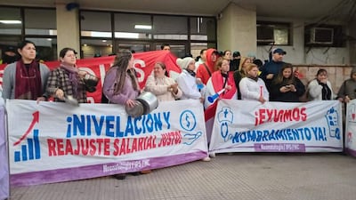 Grupo de mujeres manifestándose con pancartas que demandan reajuste salarial justo, en exterior durante una protesta.
