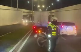 Agente de la Policía Municipal de Tránsito (PMT) redireccionando el tránsito en la avenida de la Costanera de Asunción y detrás el camión averiado.