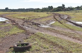 Paisaje rural en Encarnación, caminos de tierra húmedos y un neumático desgastado en un entorno semirural.