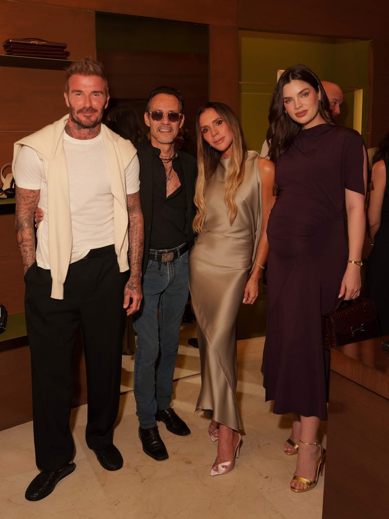 Nadia Ferreira luciendo un vestido claro y Marc Anthony con camisa negra, ambos en un ambiente elegante y sofisticado.