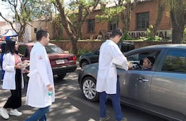 Estudiantes de medicina entregando materiales informativos a automovilistas que circulan por cercanías de la actividad.