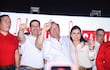 Raúl Latorre en camiseta blanca y Yamil Esgai sonriente levantan el dedo índice, mientras Camilo Pérez observa con atención en un evento festivo.