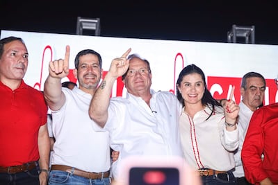 Raúl Latorre en camiseta blanca y Yamil Esgai sonriente levantan el dedo índice, mientras Camilo Pérez observa con atención en un evento festivo.